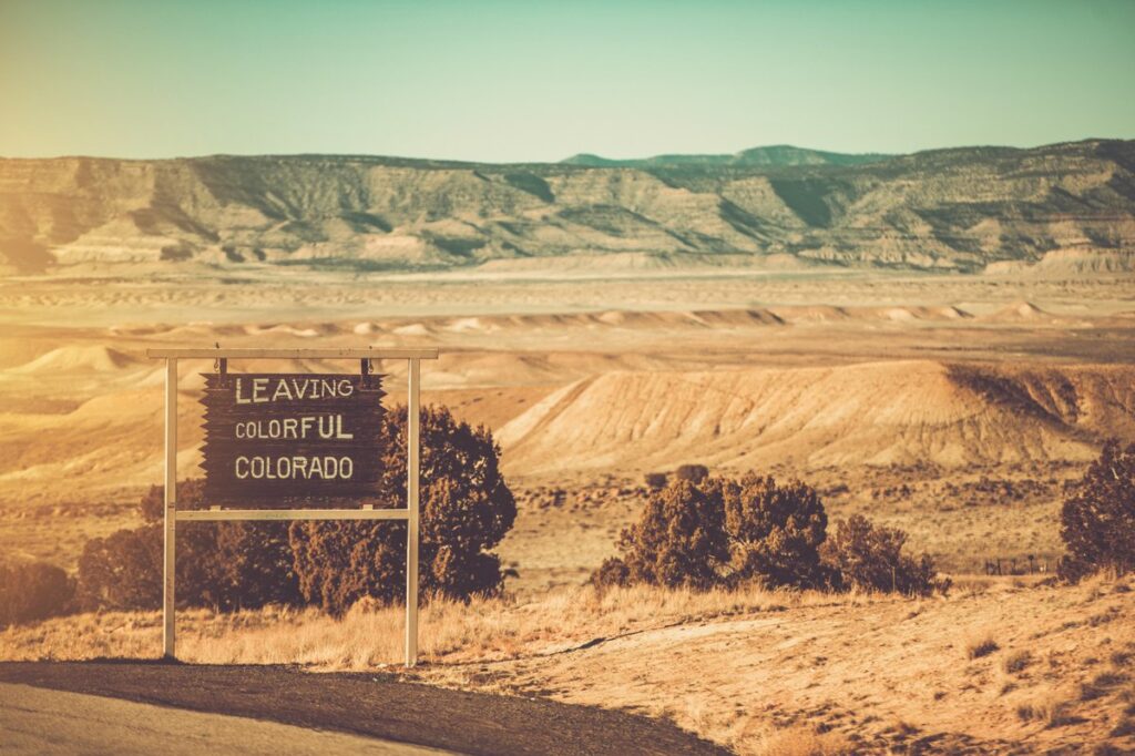 Leaving Colorful Colorado sign near the Utah border, perfect for a rent a car road trip adventure through stunning landscapes.